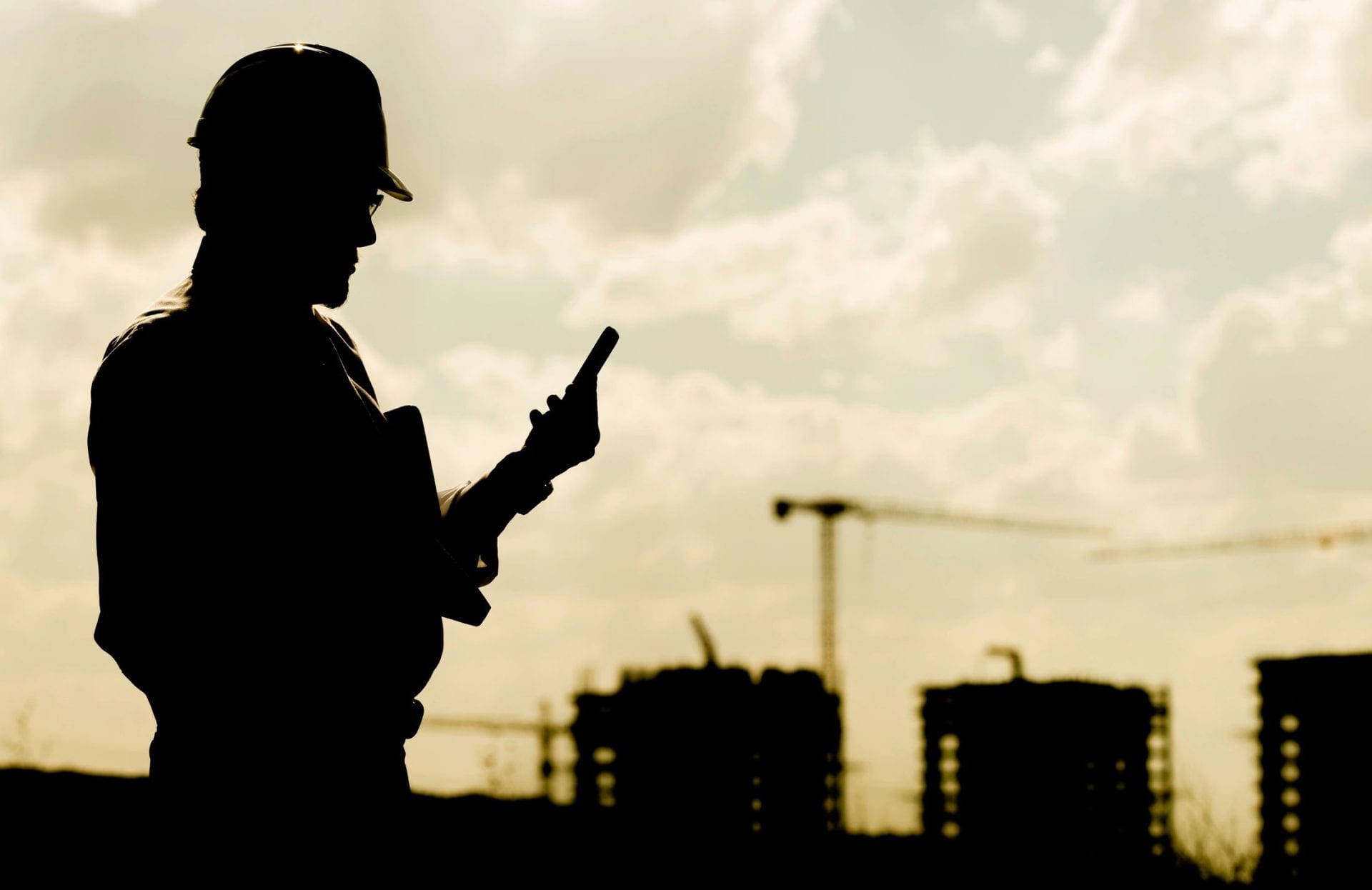 A man in hard hat looking at his cell phone.